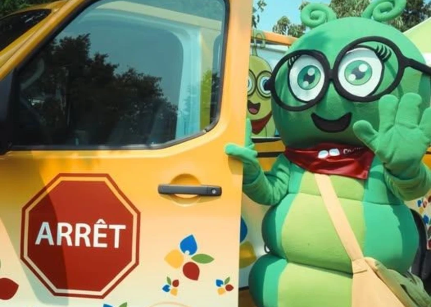 Camille La chenille, la mascotte du conseil devant son bus jaune du CECCE